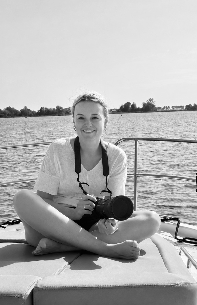 Zwart-wit profielfoto van een persoon met camera op een boot, met water op de achtergrond